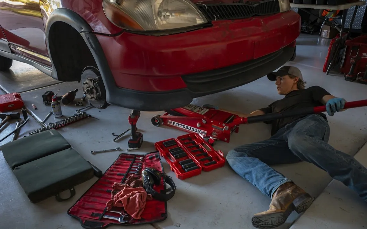 Motor mechanic working under a car in a garage workshop